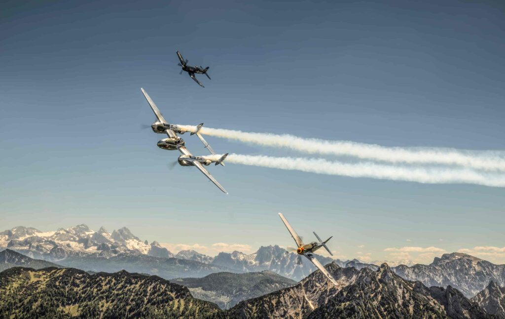 Drei Flugzeuge der The Flying Bulls fliegen über Berge