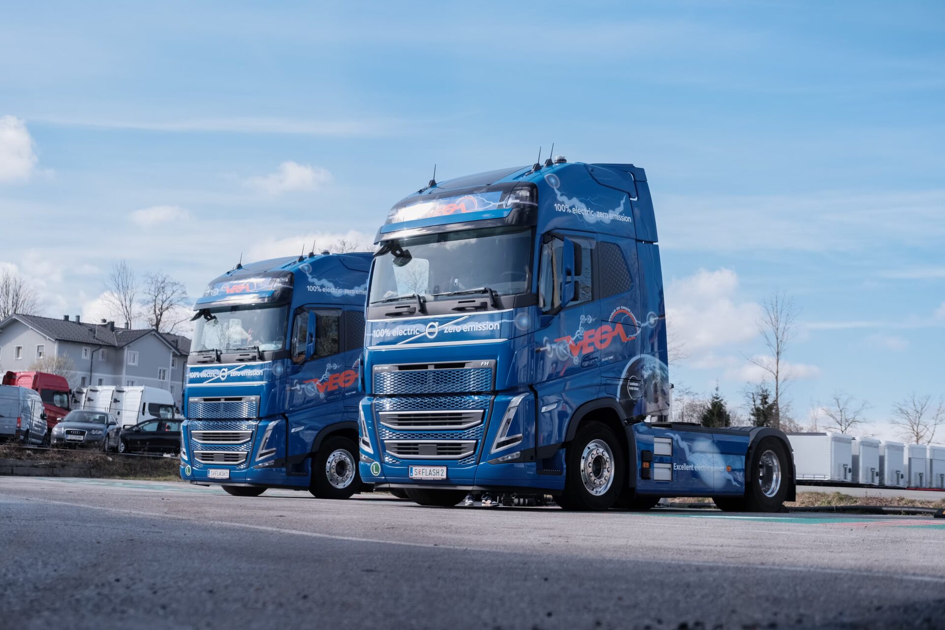 Zwei LKW von VEGA International stehen auf einem Parkplatz