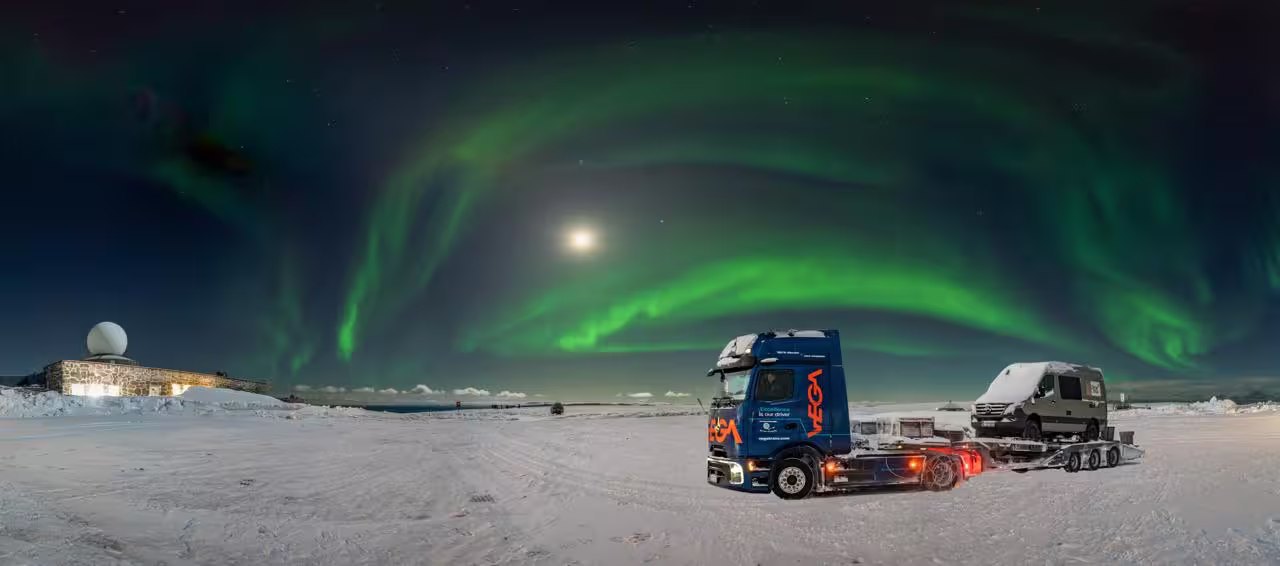1 Vega International LKW steht bei einer Wetterstation auf Schnee, im Hintergrund Polarlichter
